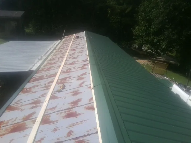 Old rusted panels beside newly installed green metal roofing — Wind Damage Roof Repair by Roofing Brothers in Glendora